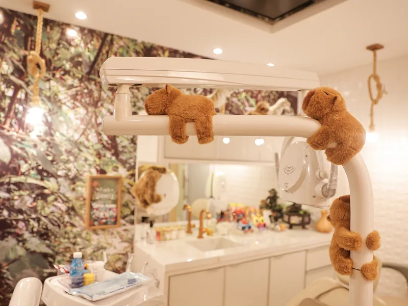 Consultório da Adelar Kids com refletor decorado com macacos de pelúcia e parede com painel de floresta